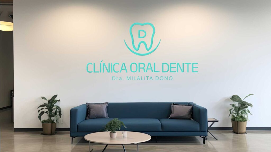 Aplicação da identidade visual da Clínica Oral Dente na parede de uma sala de receção moderna, com logo centralizado sobre sofá azul e plantas decorativas.